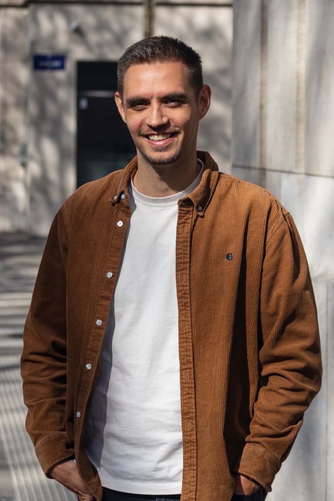 Justin Bériot, smiling in a brown corduroy shirt in front of a stone facade