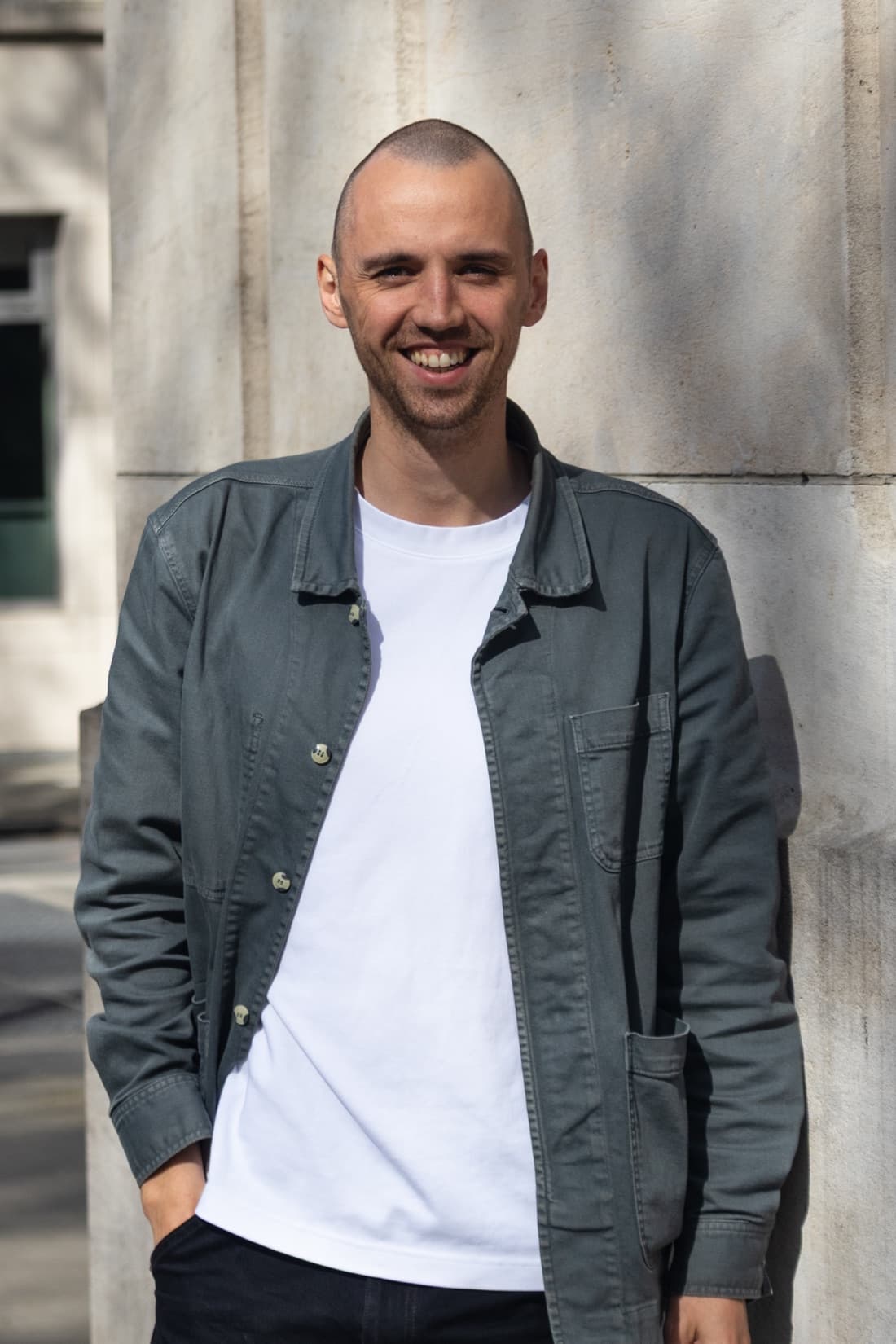Max Rymen, smiling in a grey jacket in front of a stone facade